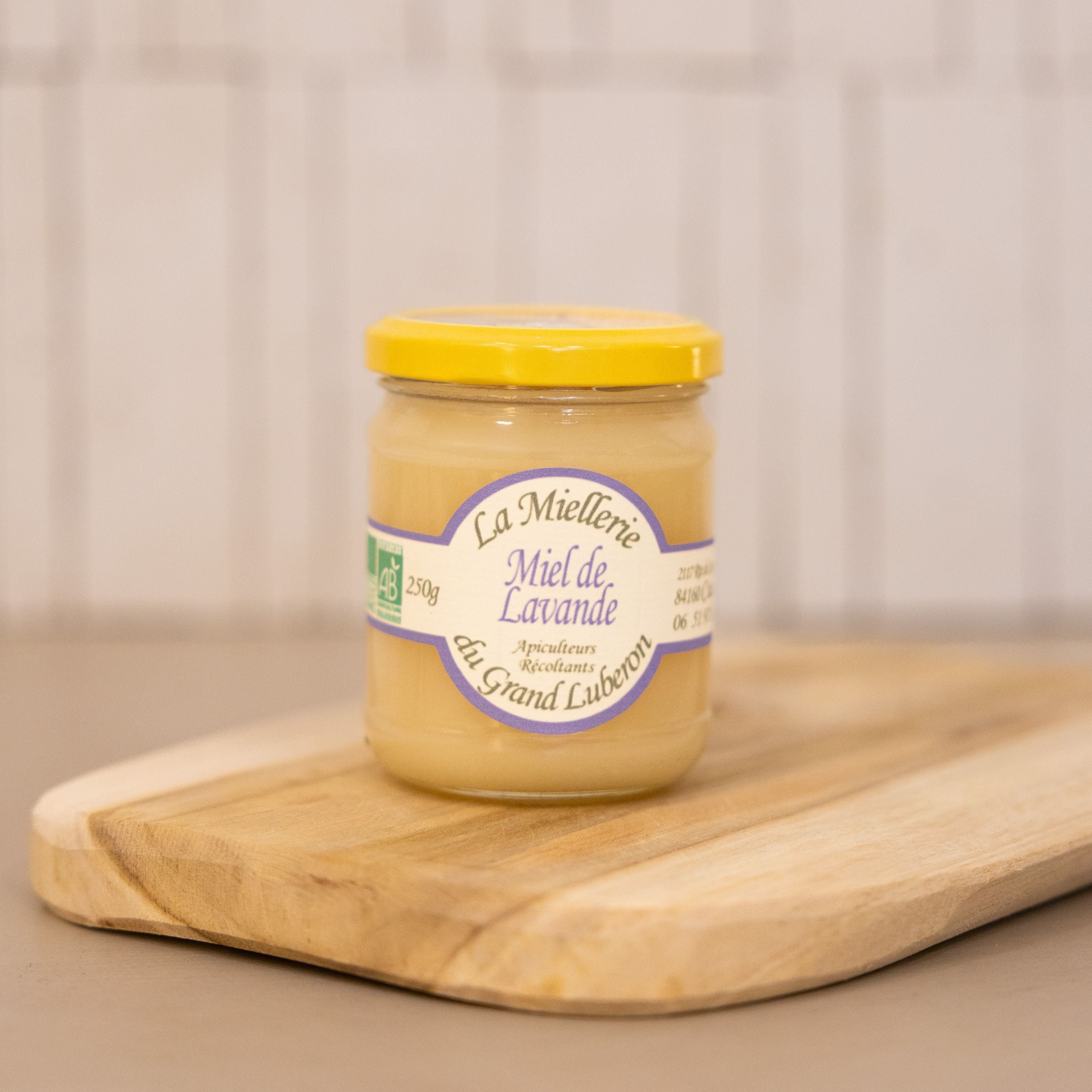 A jar of organic lavender honey from a family farm in the Luberon, with a wooden honey dipper.
