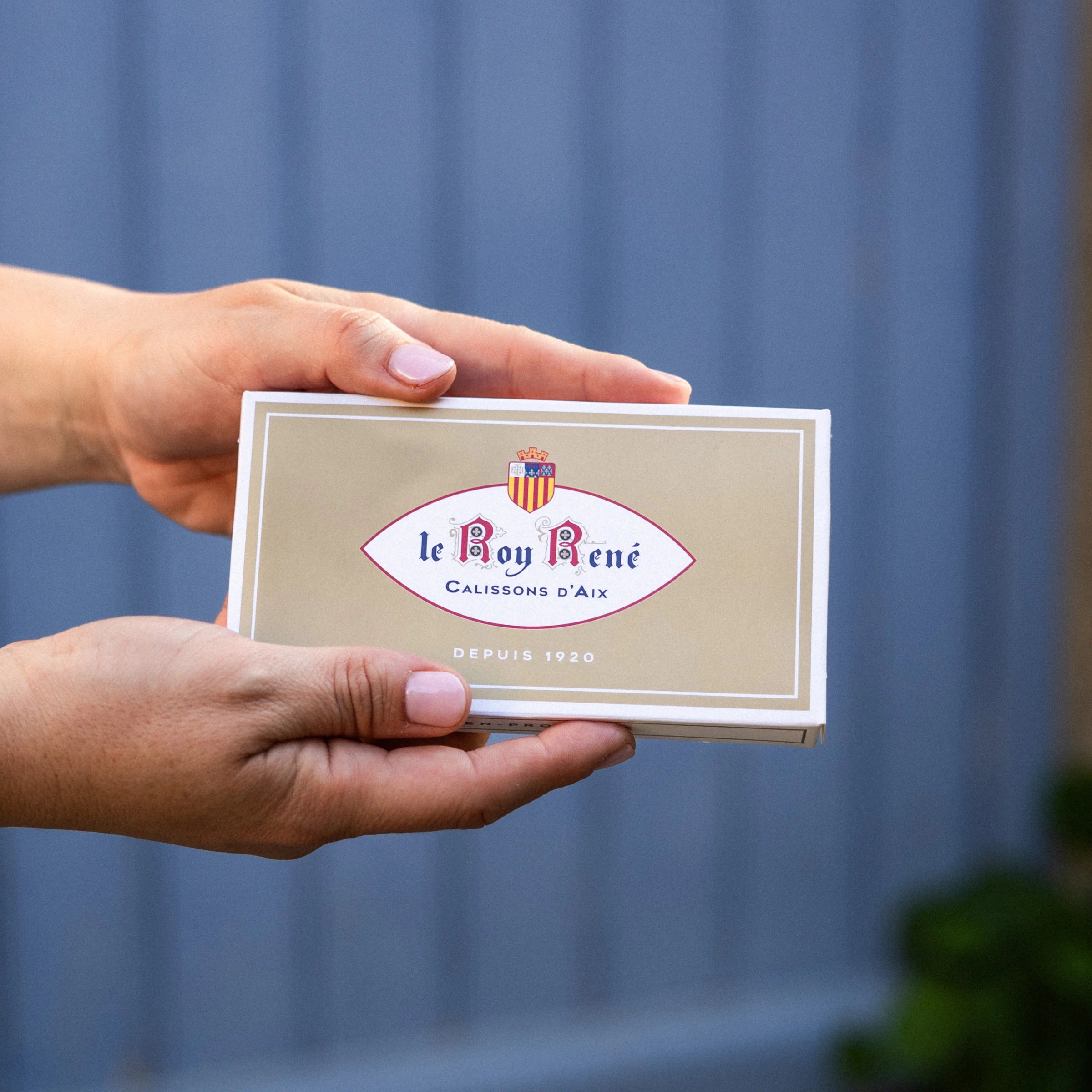 Hands holding a Le Roy René Calissons d'Aix box, traditional Provençal confectionery since 1920