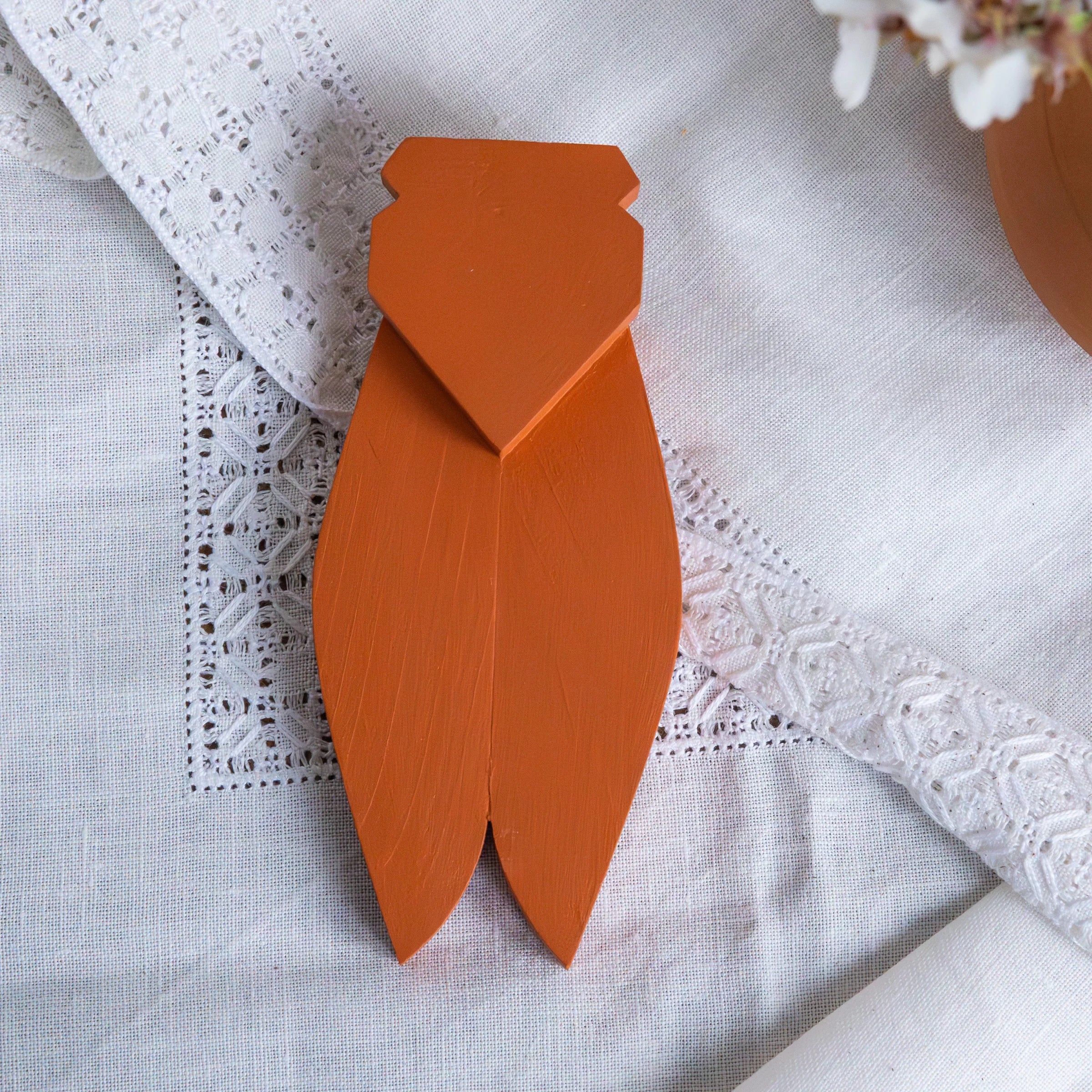 Terracotta painted wooden cicada by AnimOC front view on white embroidered fabric, handcrafted Provençal decoration