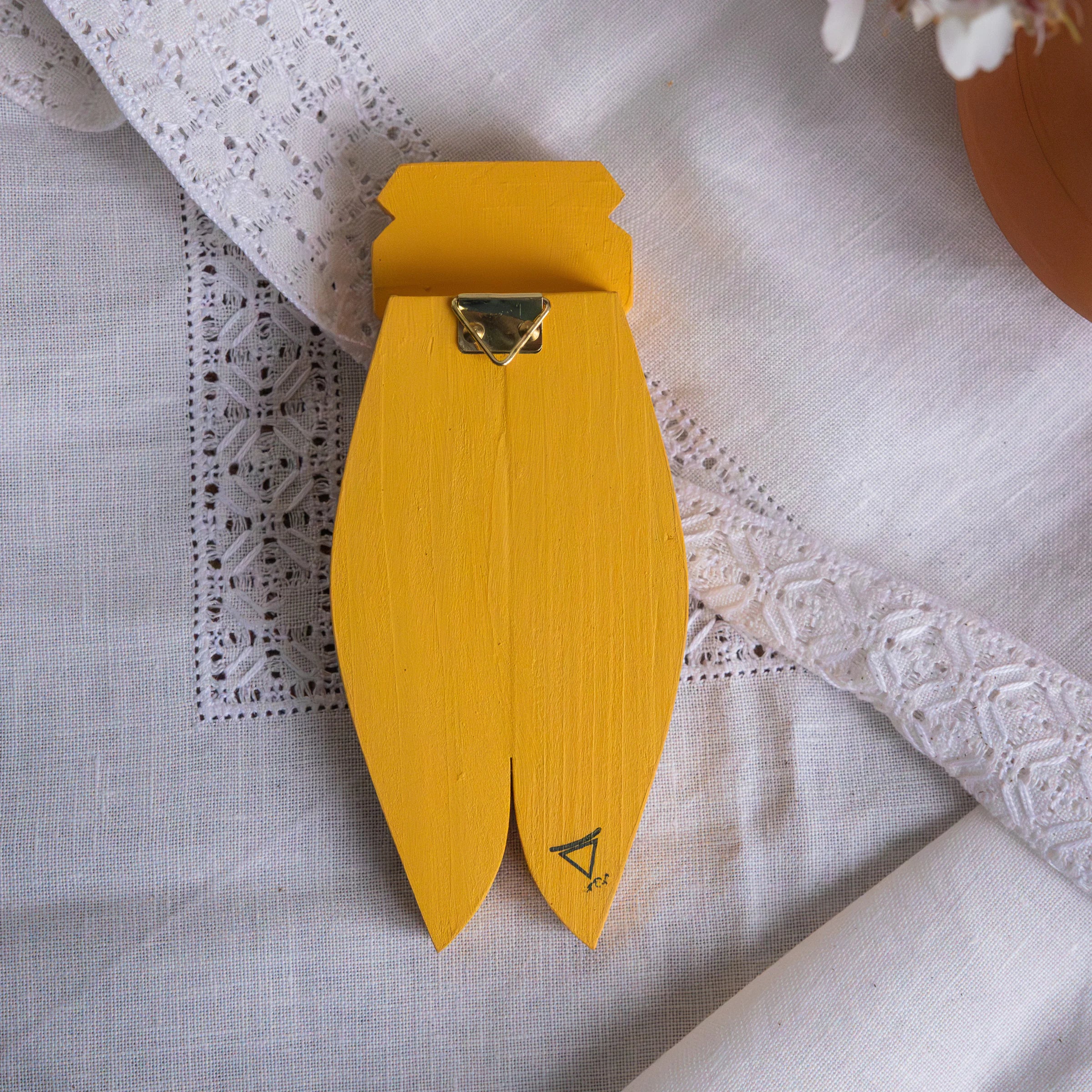 Back view of yellow AnimOC wooden cicada showing gold hanging triangle and engraved logo, Provençal wall art