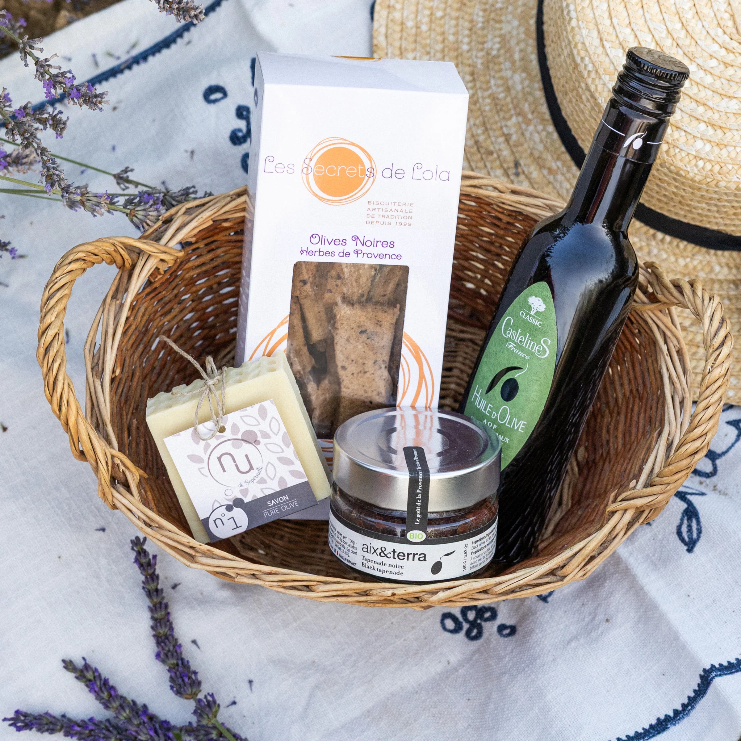 Discover Olives gift box with black olive biscuits, AOP olive oil, organic black tapenade and pure olive soap in a wicker basket with Provençal fabric