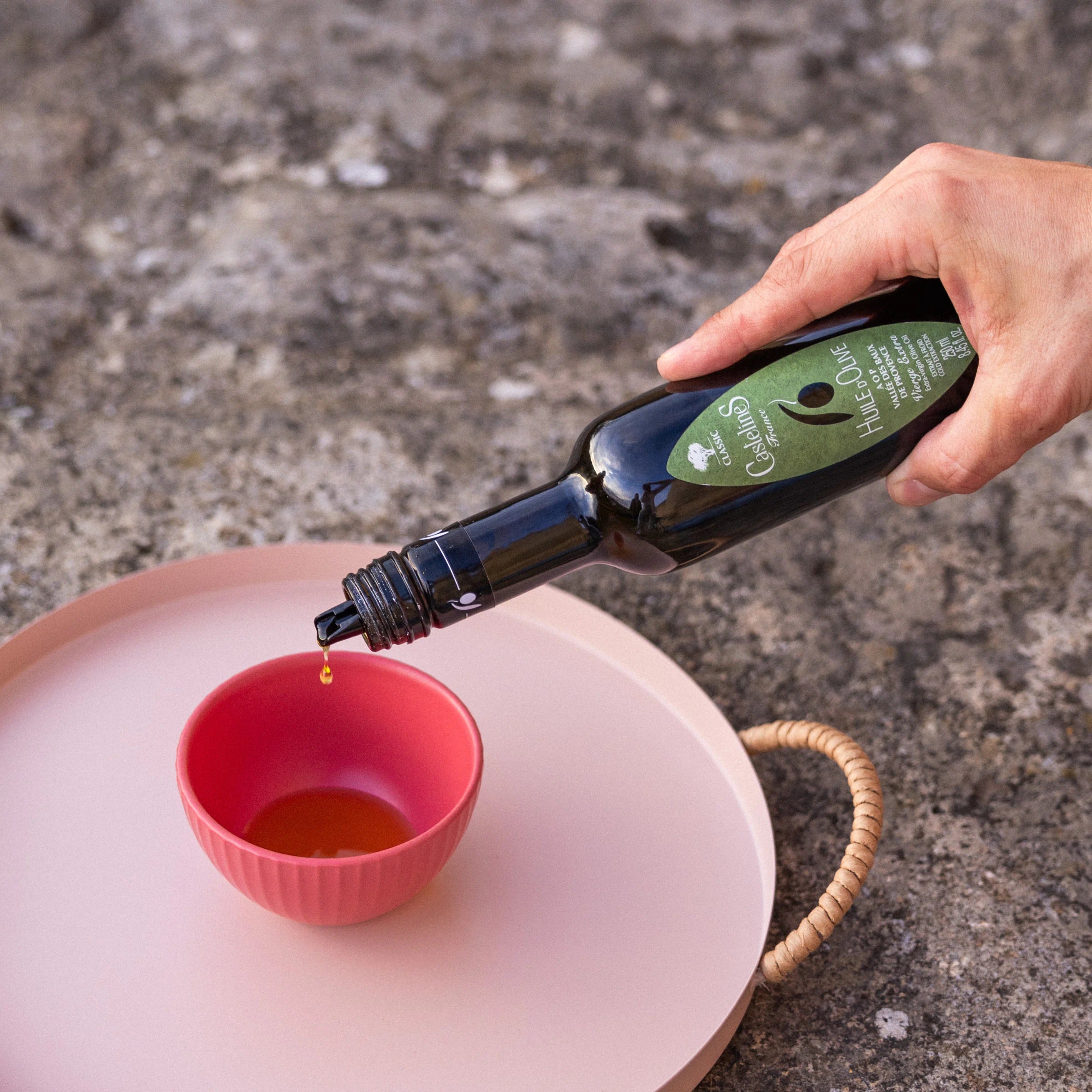 Pouring Castelines AOP extra virgin olive oil from Provence into a small ceramic bowl
