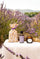 Lavender Season banner with lavender pouch, Lavandin Grosso essential oil and lavender scented candle on a linen table in a Provençal lavender field