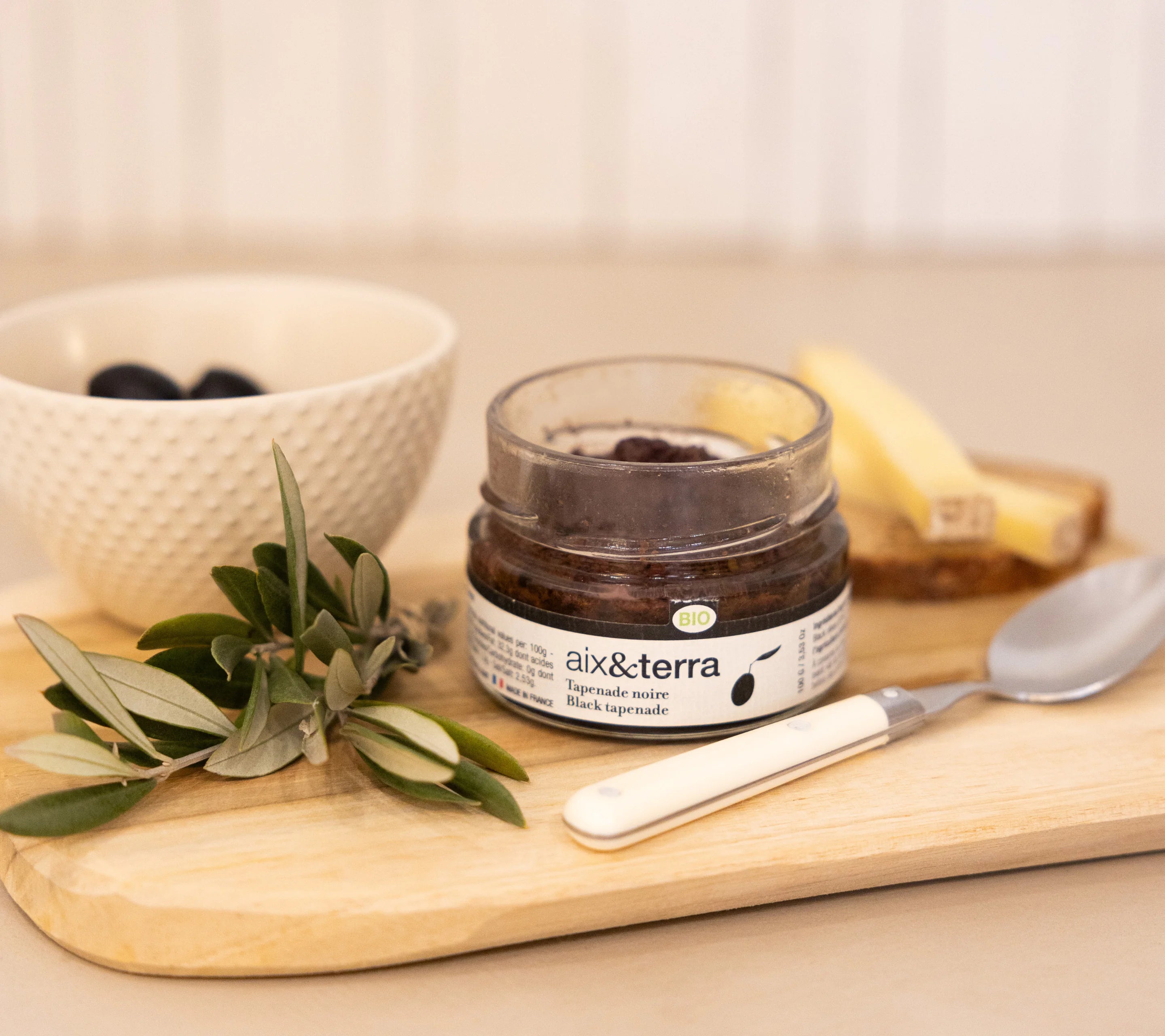 Aix&Terra organic black tapenade paired with crispy bread and fresh olive branch, Provençal aperitif
