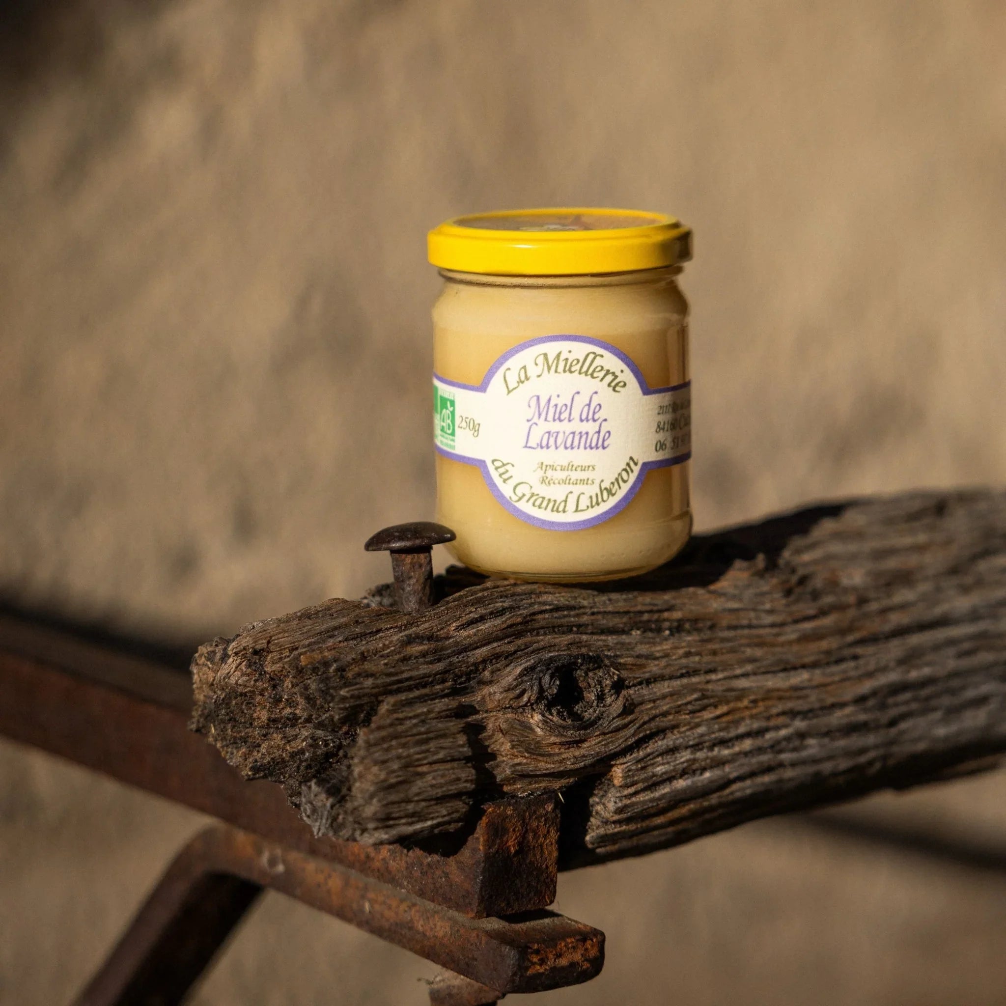 A jar of organic lavender honey from a family farm in the Luberon, with a wooden honey dipper.