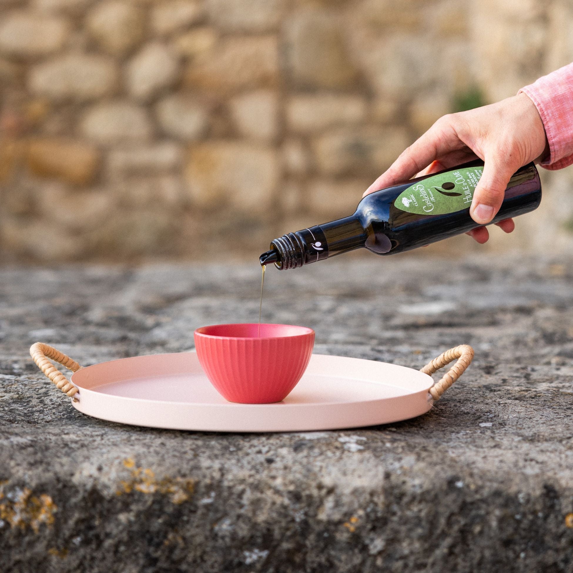 A close-up of a rustic Provençal seasoning ritual, featuring a drizzle of AOP extra virgin olive oil over fresh bread, alongside authentic French Fleur de Sel and organic Herbes de Provence, representing Céline en Provence.
