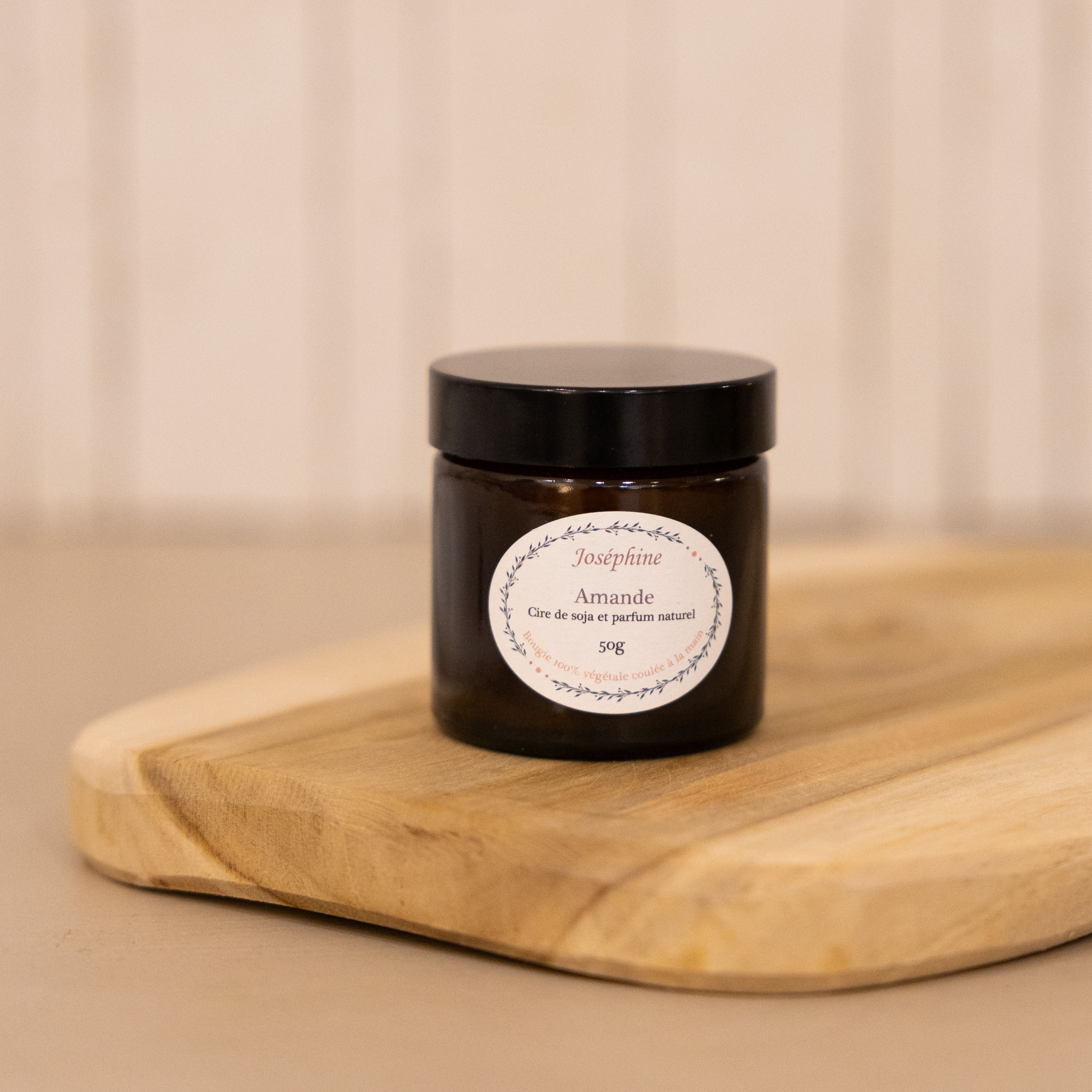 A handmade almond scented candle from Provence, with notes of orange blossom and vanilla, shown lit in a cosy home setting.

