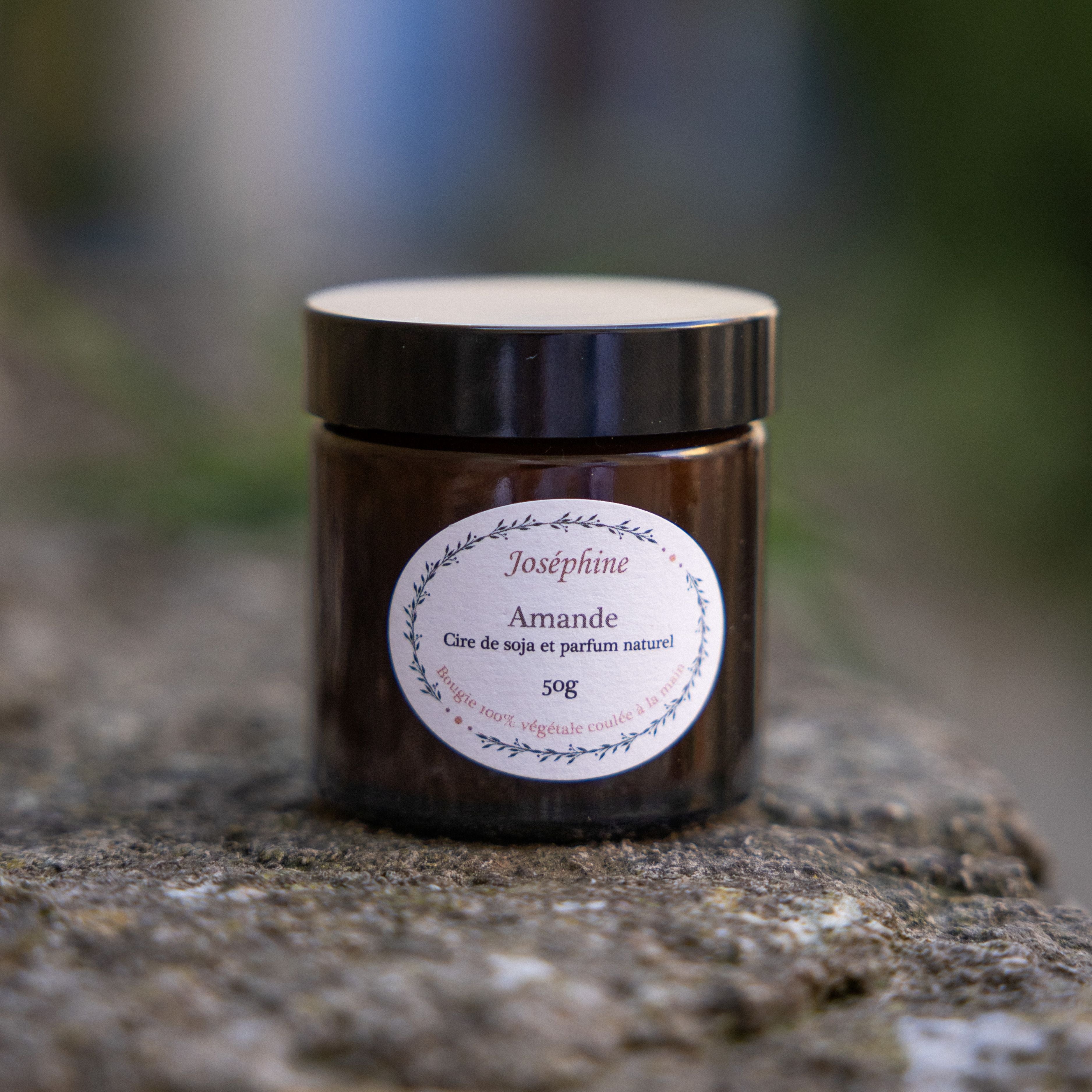 A handmade almond scented candle from Provence, with notes of orange blossom and vanilla, shown lit in a cosy home setting.