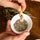 Hands using a wooden salt spoon to scoop Fleur de Sel with Provence herbs from a white bowl